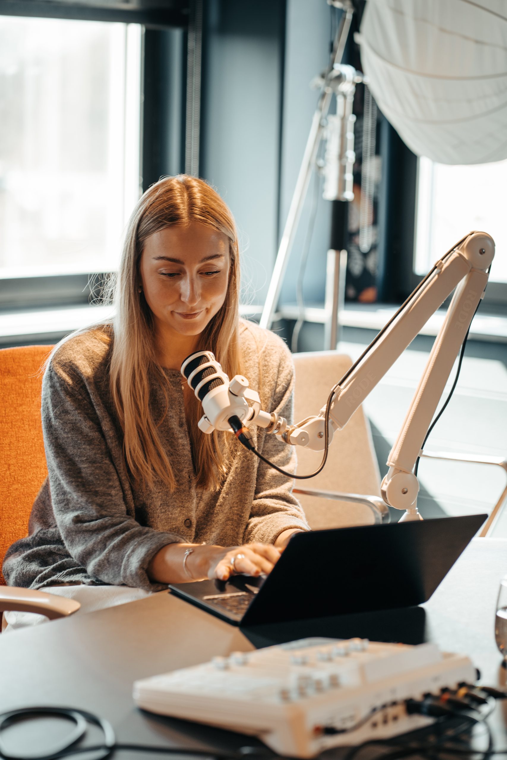 Kvinna som sitter framför en mic och en laptop